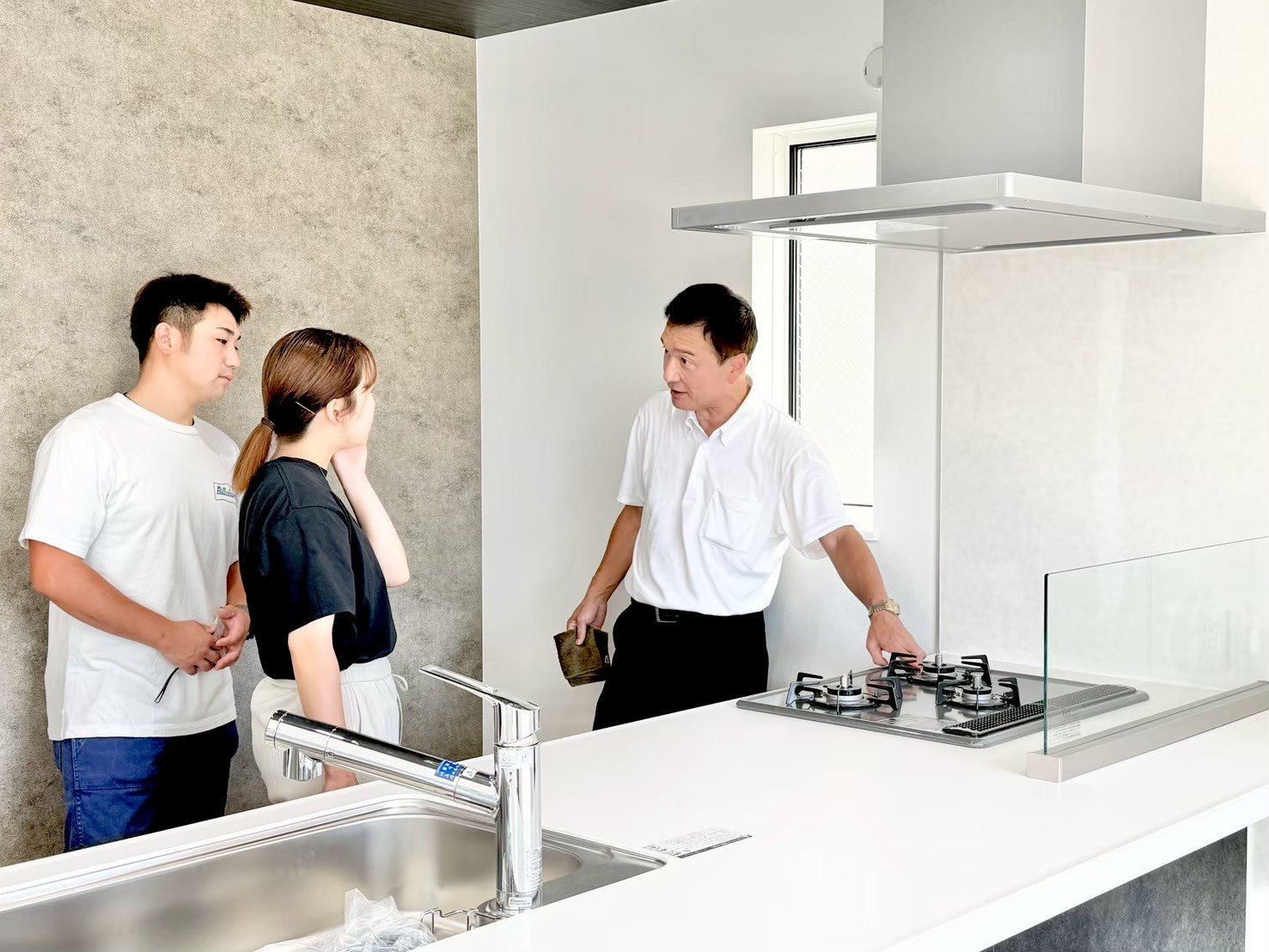 新築戸建てのキッチン設備について説明を受けるご夫婦