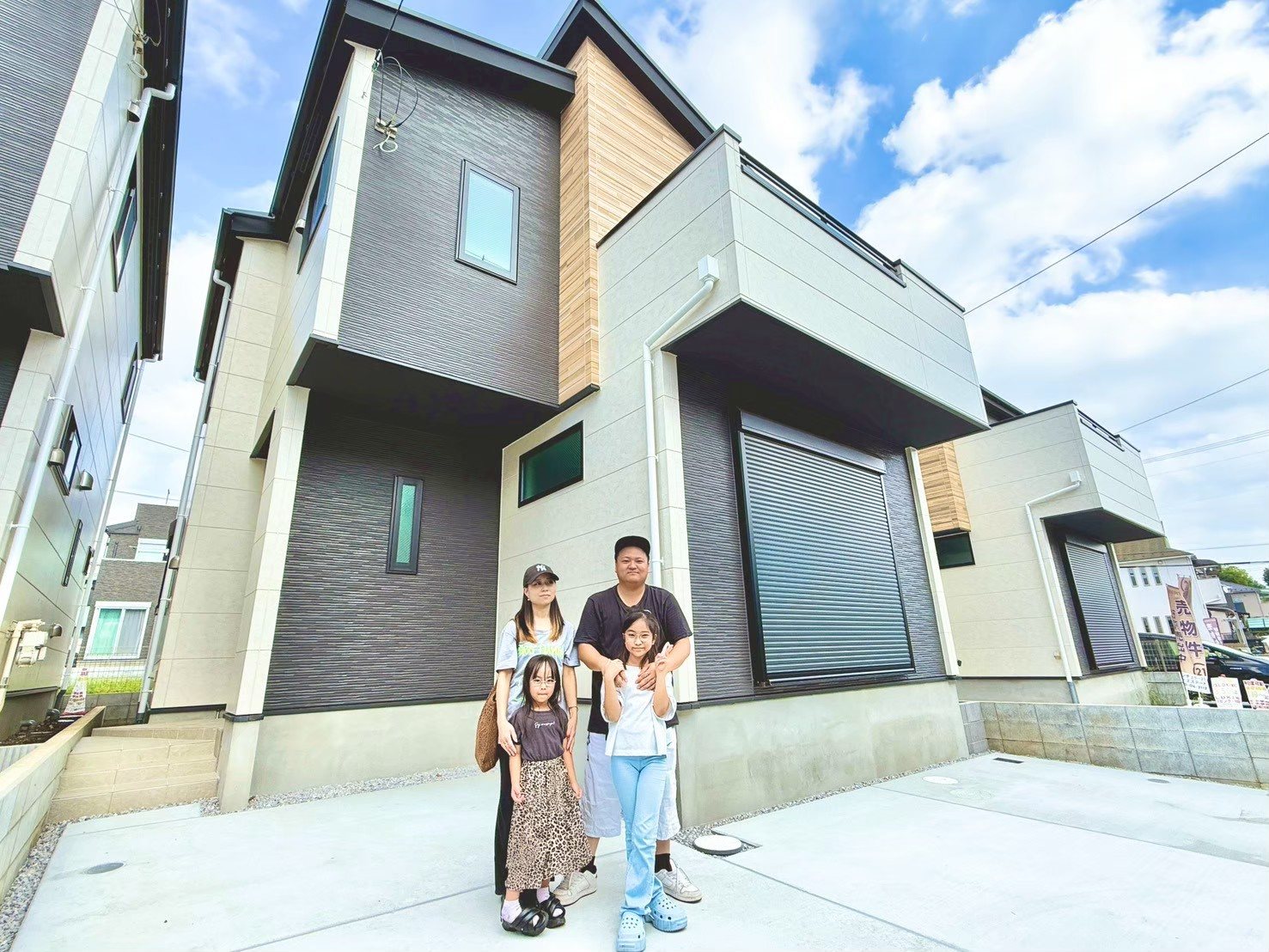 新しい戸建ての前で記念撮影をするご家族