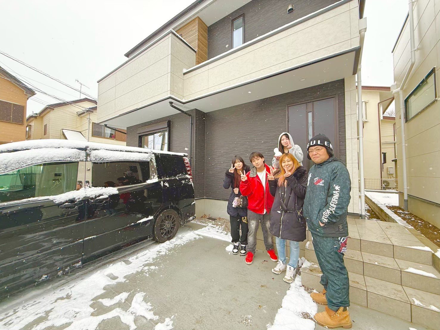 雪の日に新居の前で記念撮影をするご家族